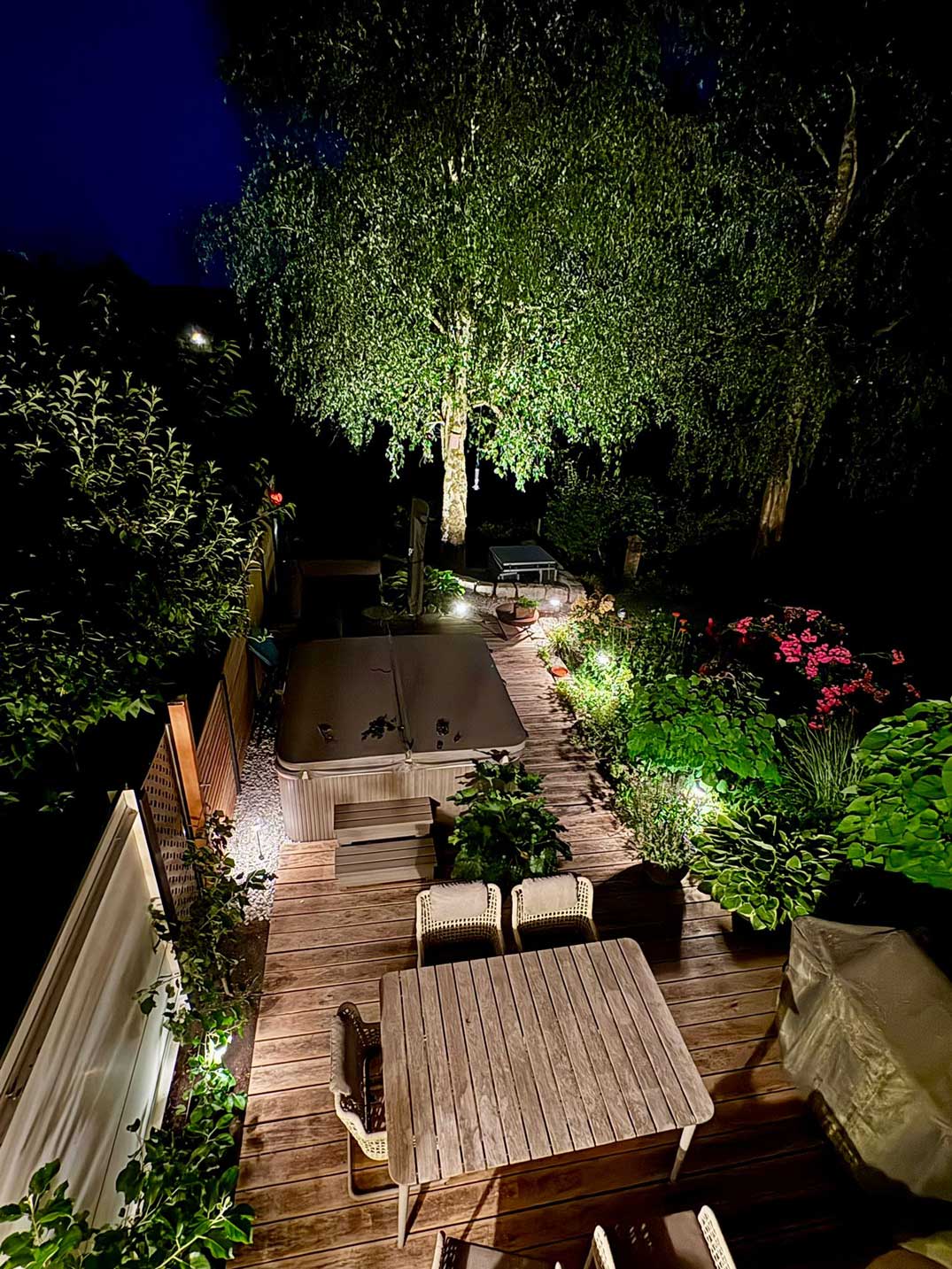 Gartenbeleuchtung in München mit beleuchtetem Baum, Terrasse, Whirlpool und bepflanztem Gartenbereich
